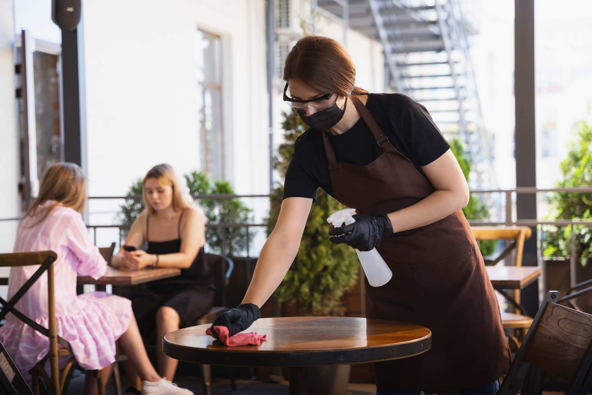 Restaurant post-covid strategies, waiter disinfecting a table