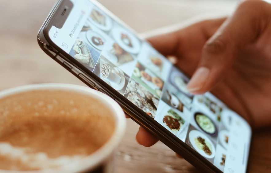 Phone with a social media feed and a cup of coffee - social media for restaurants