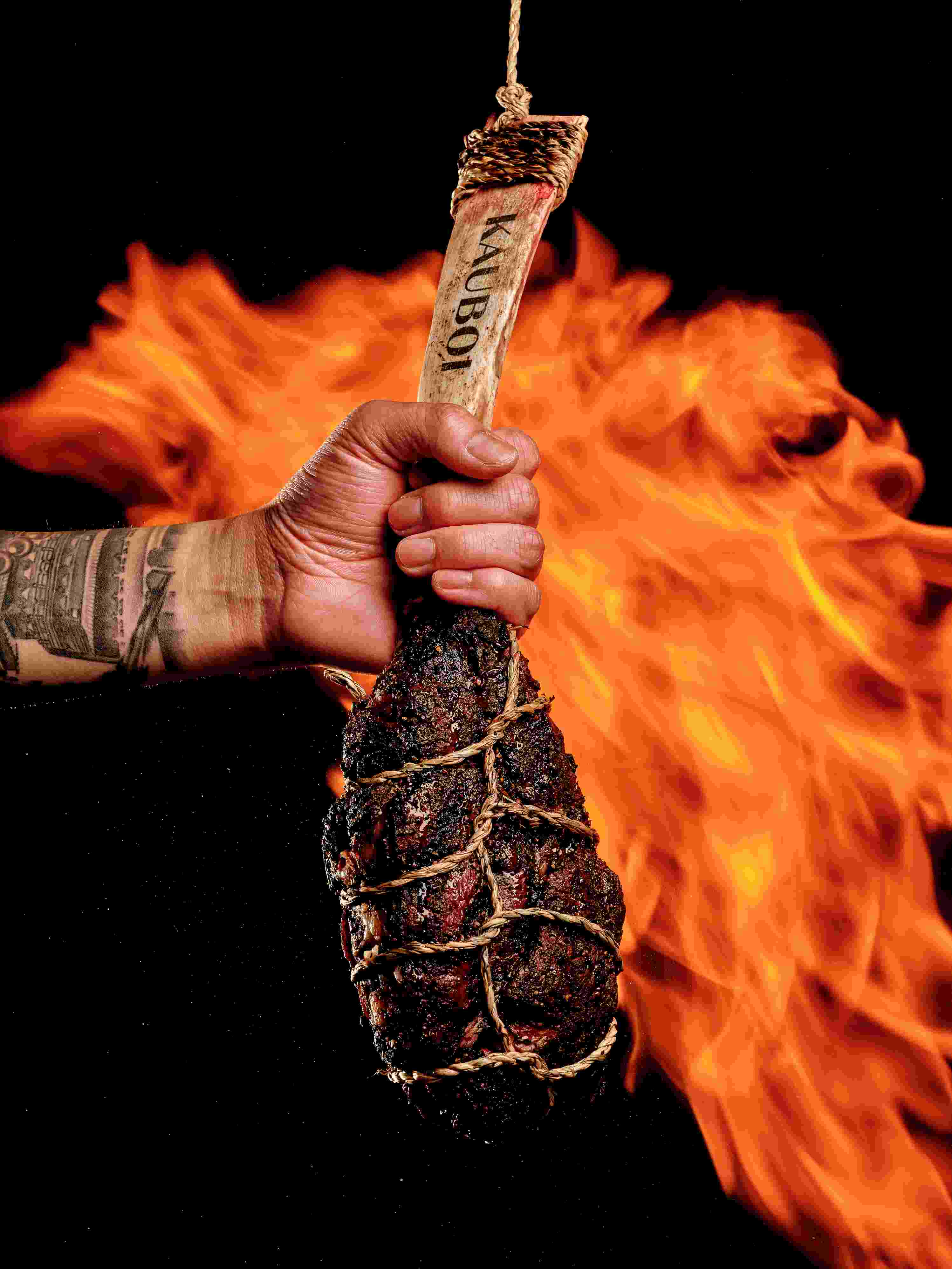 Bone-in steak held over open flame at KAUBOI