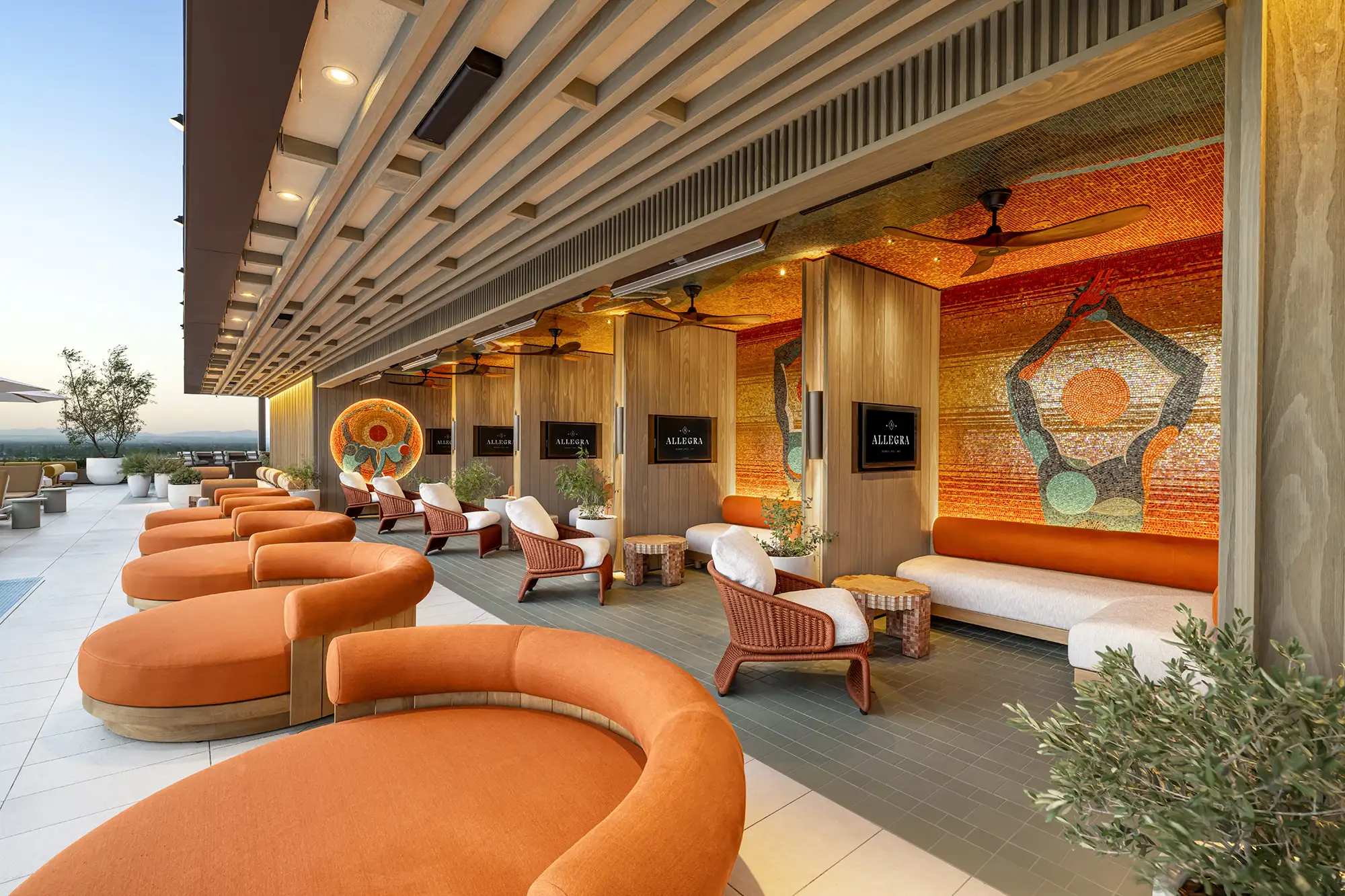 Allegra rooftop lounge with curved orange seating and a mosaic wall