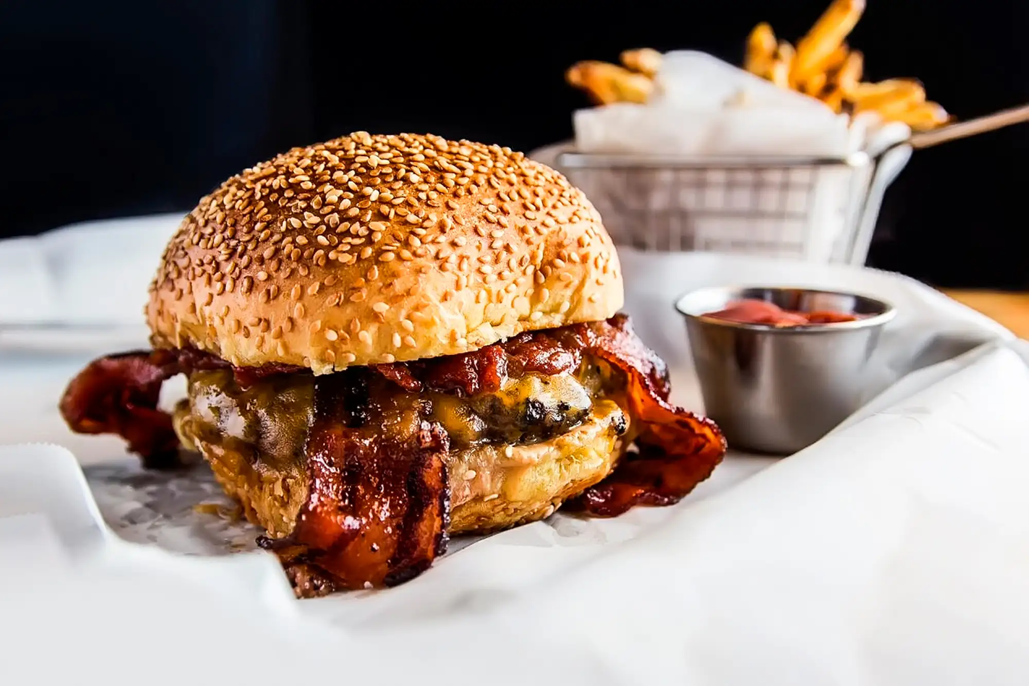 Bacon cheeseburger on a sesame bun with fries at BRGR STOP