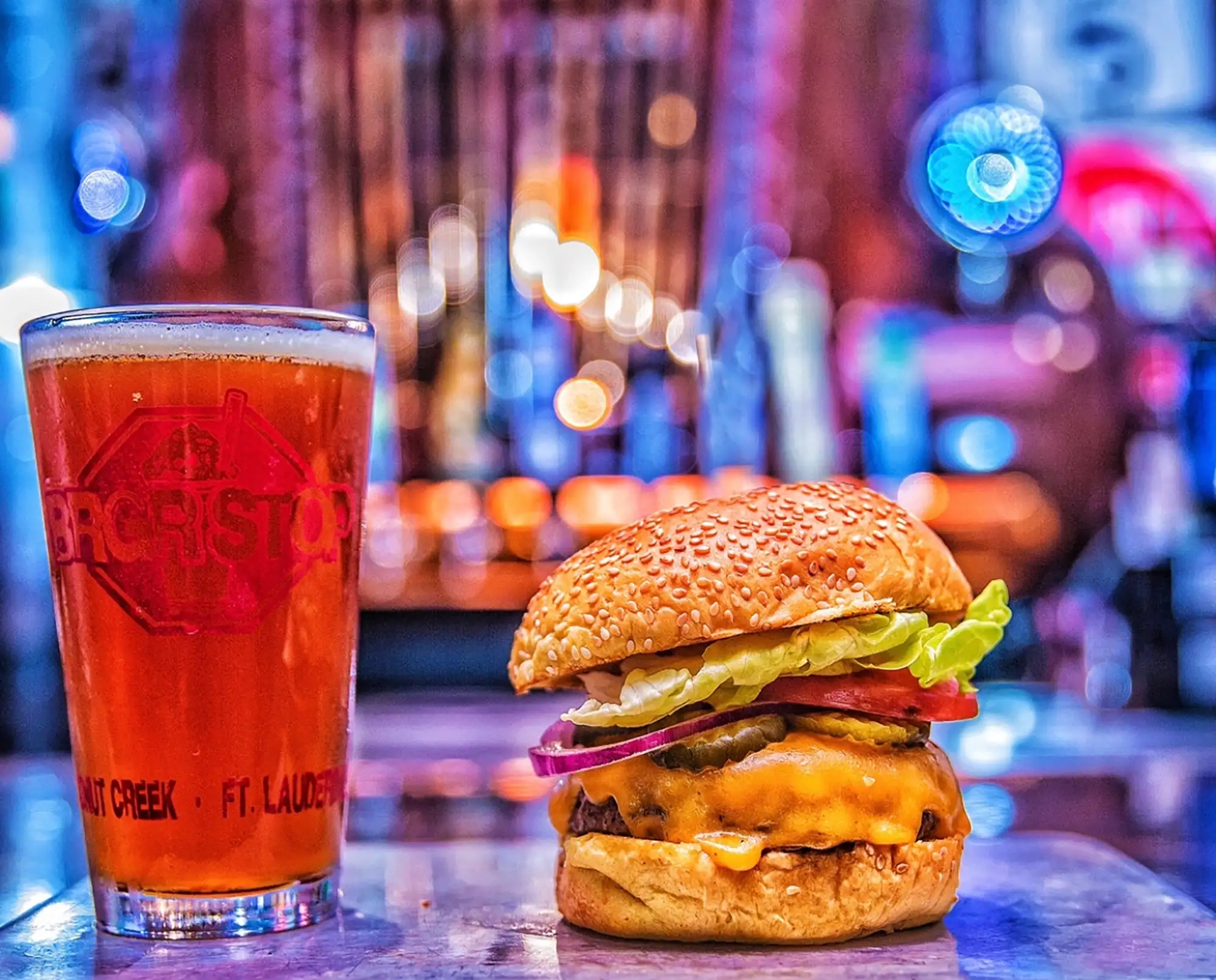 Pint of amber beer in a BRGR STOP glass next to a cheeseburger
