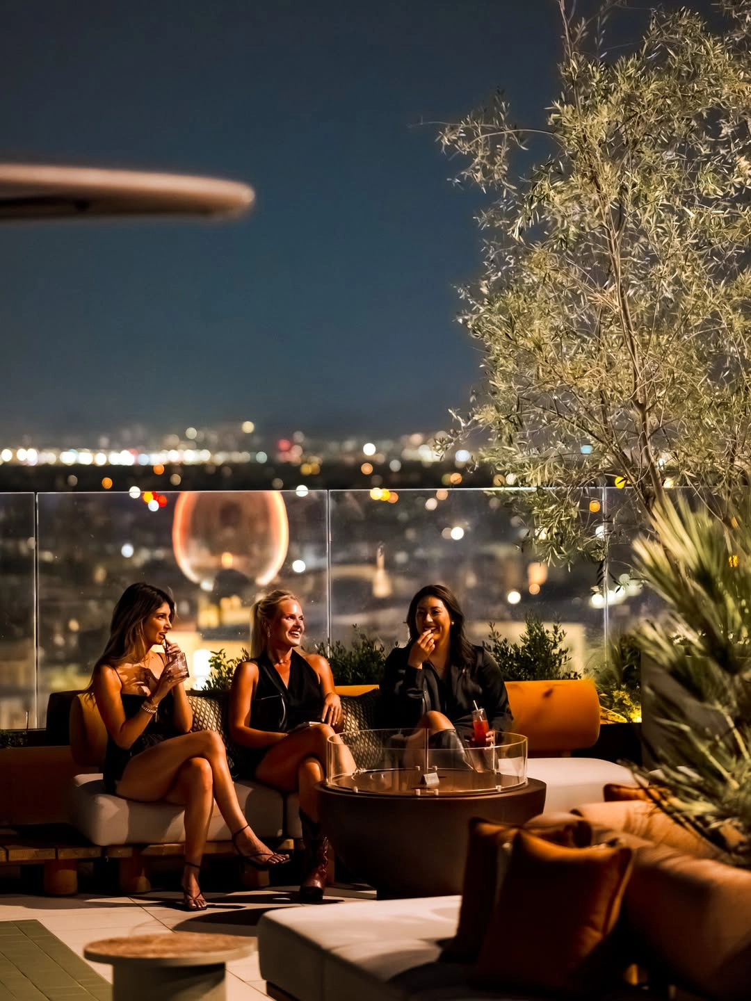 Friends at a lounge table on the Allegra rooftop at night