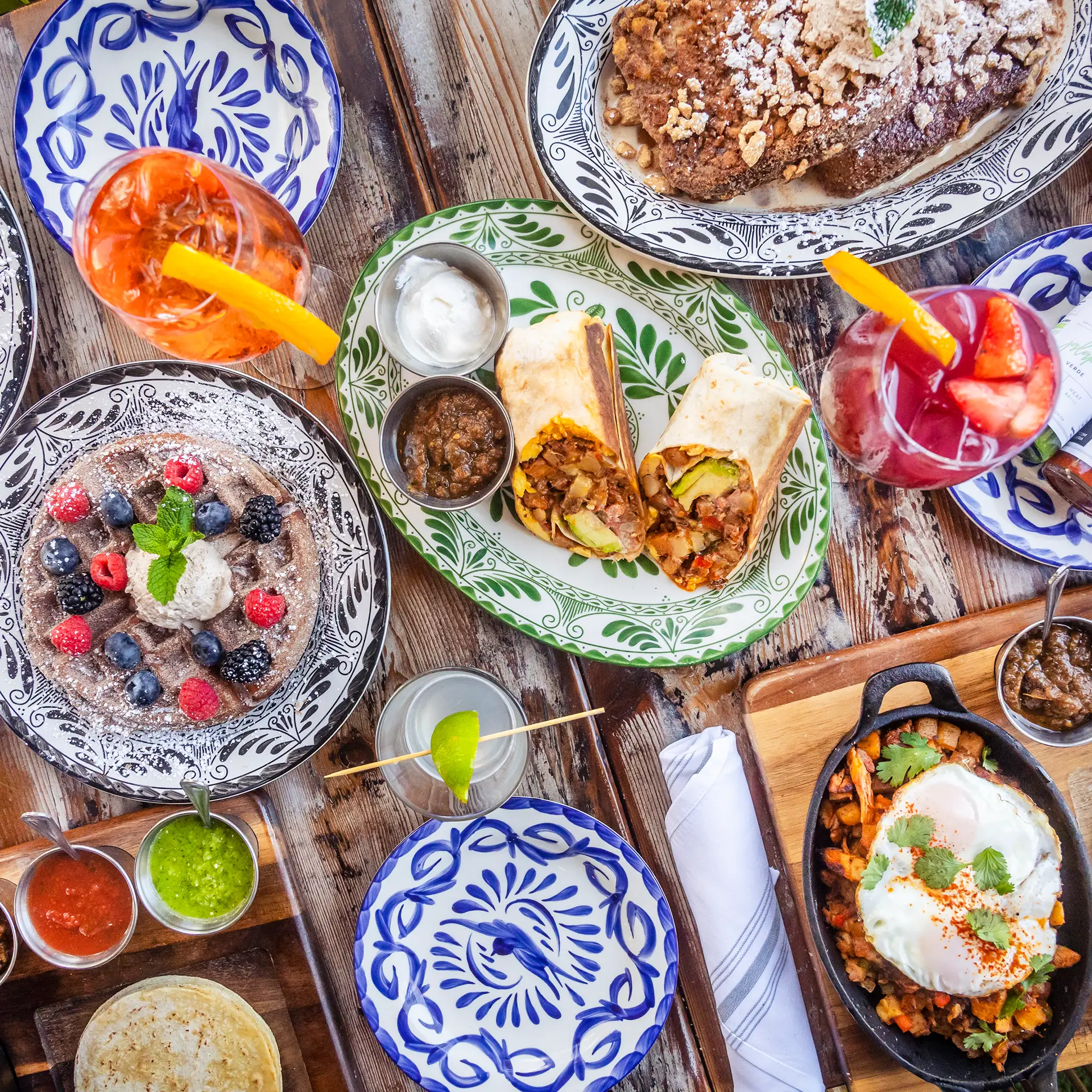Tacocraft weekend brunch spread with a breakfast burrito, a fried egg skillet, berries and cocktails