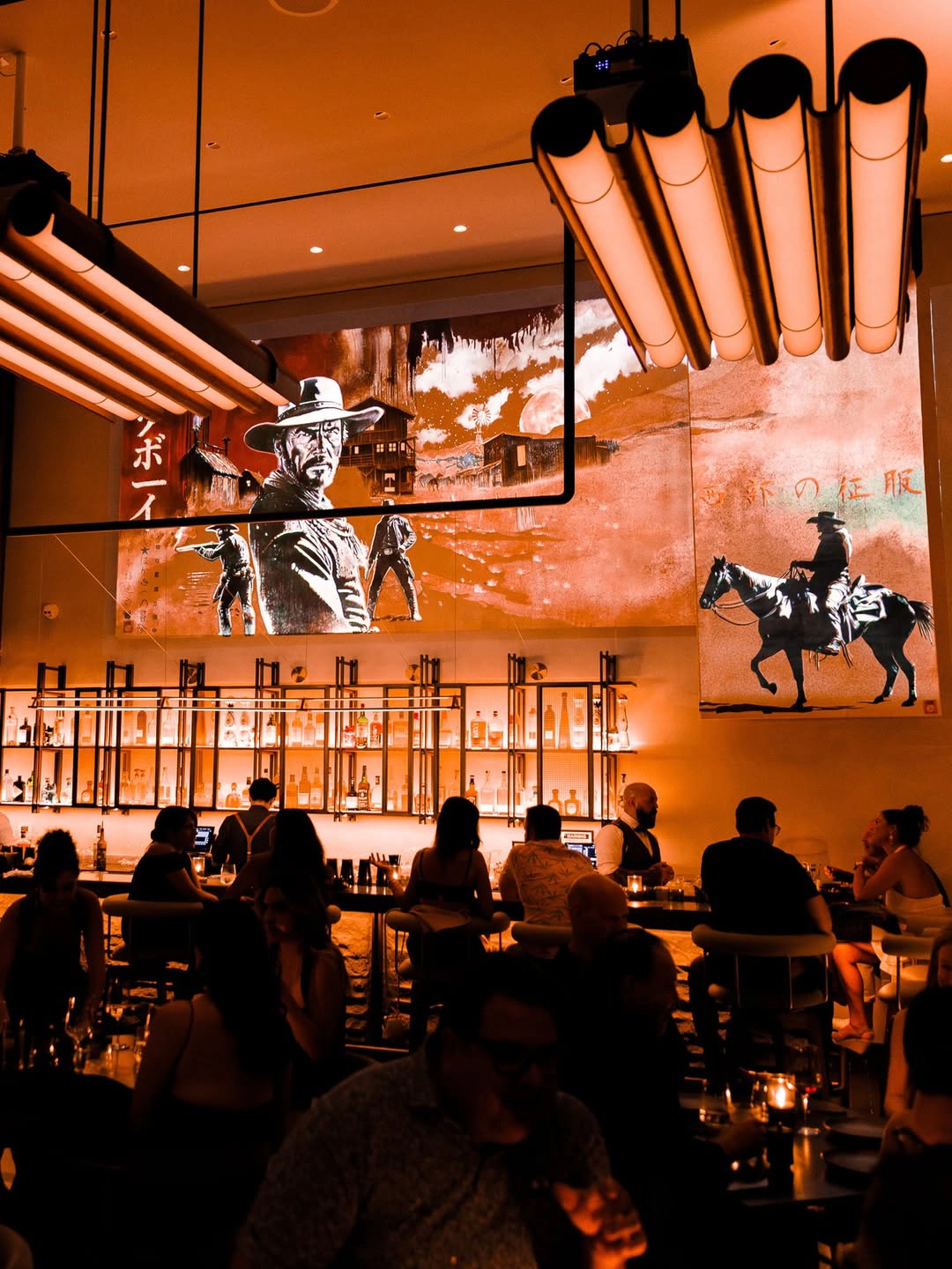 KAUBOI bar at night with western murals behind the back bar